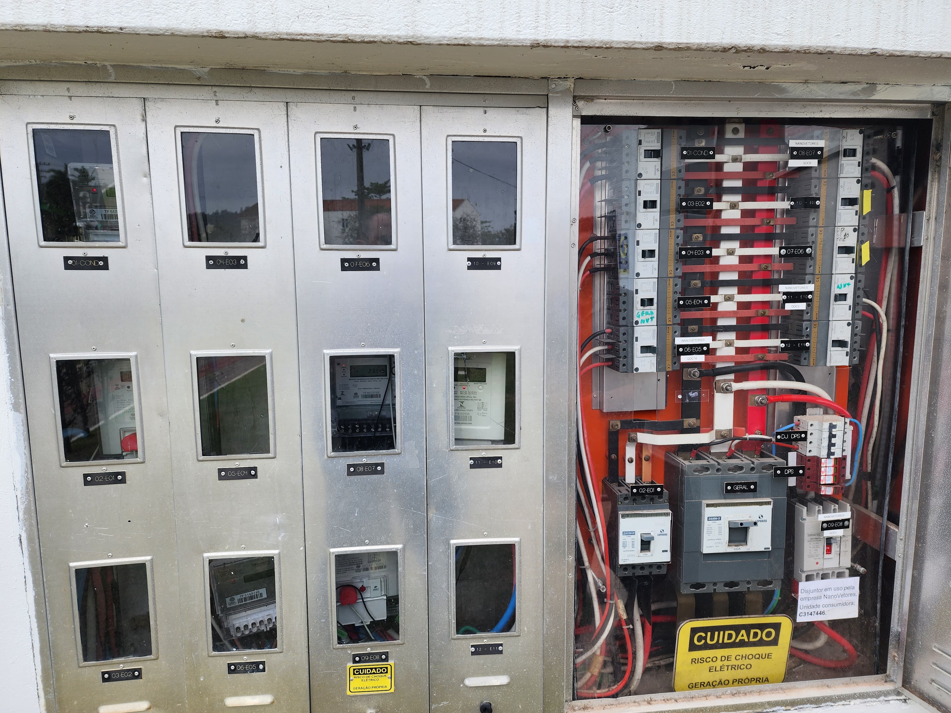 Padrão de entrada com medidores e quadro de distribuição — placa CUIDADO RISCO DE CHOQUE