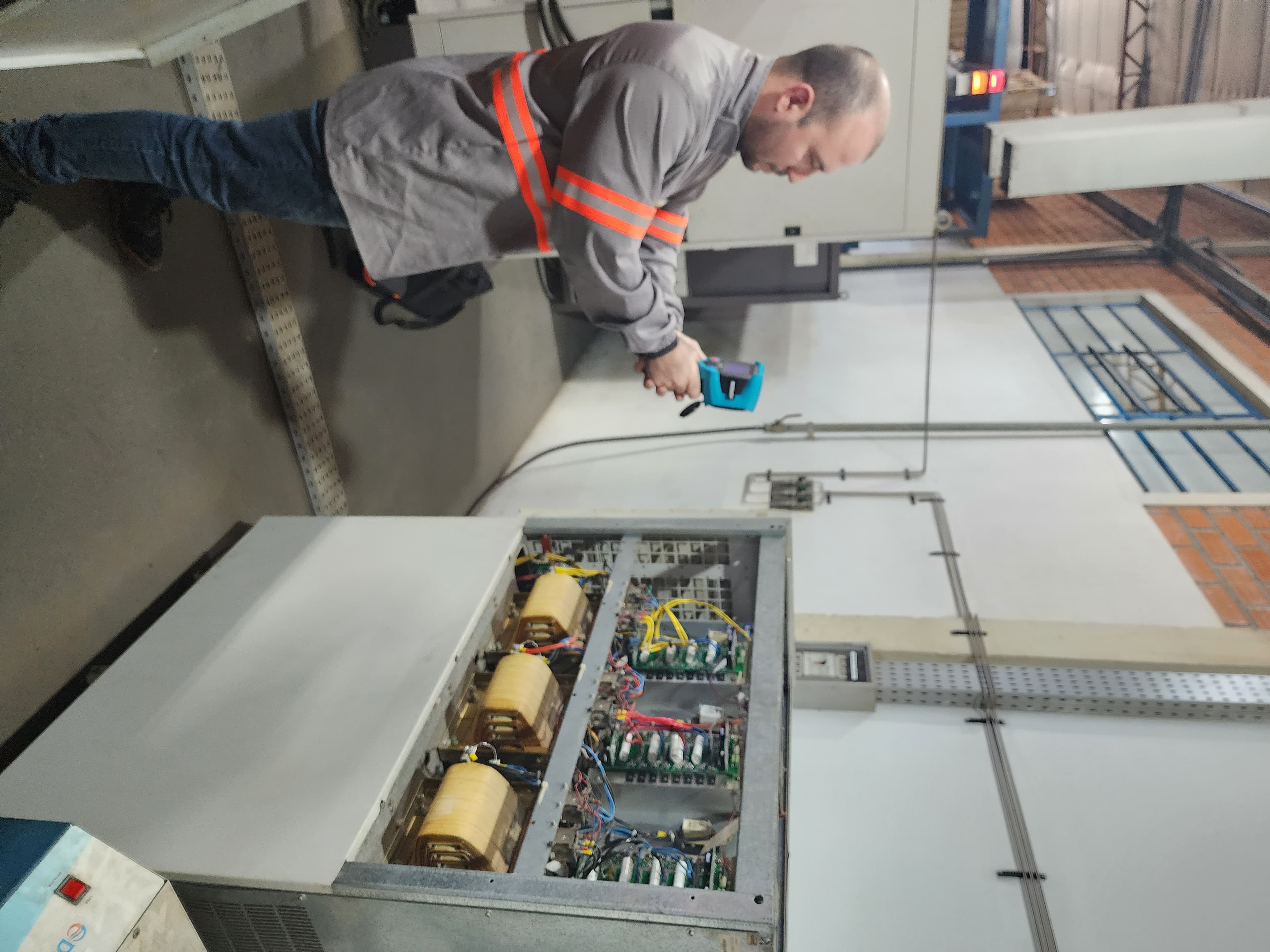 Técnico com EPI realizando medição em painel industrial — análise de riscos elétricos